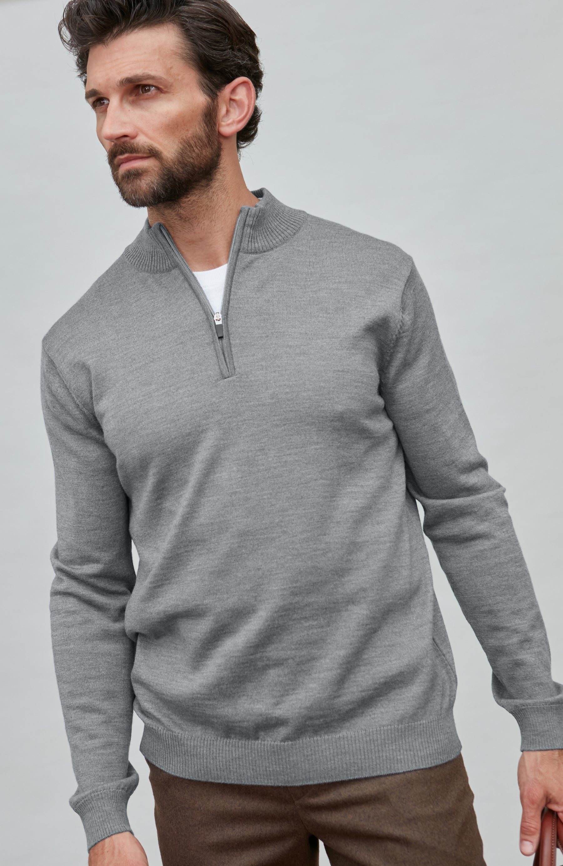 Man wearing a gray merino wool quarter-zip sweater against a light gray background