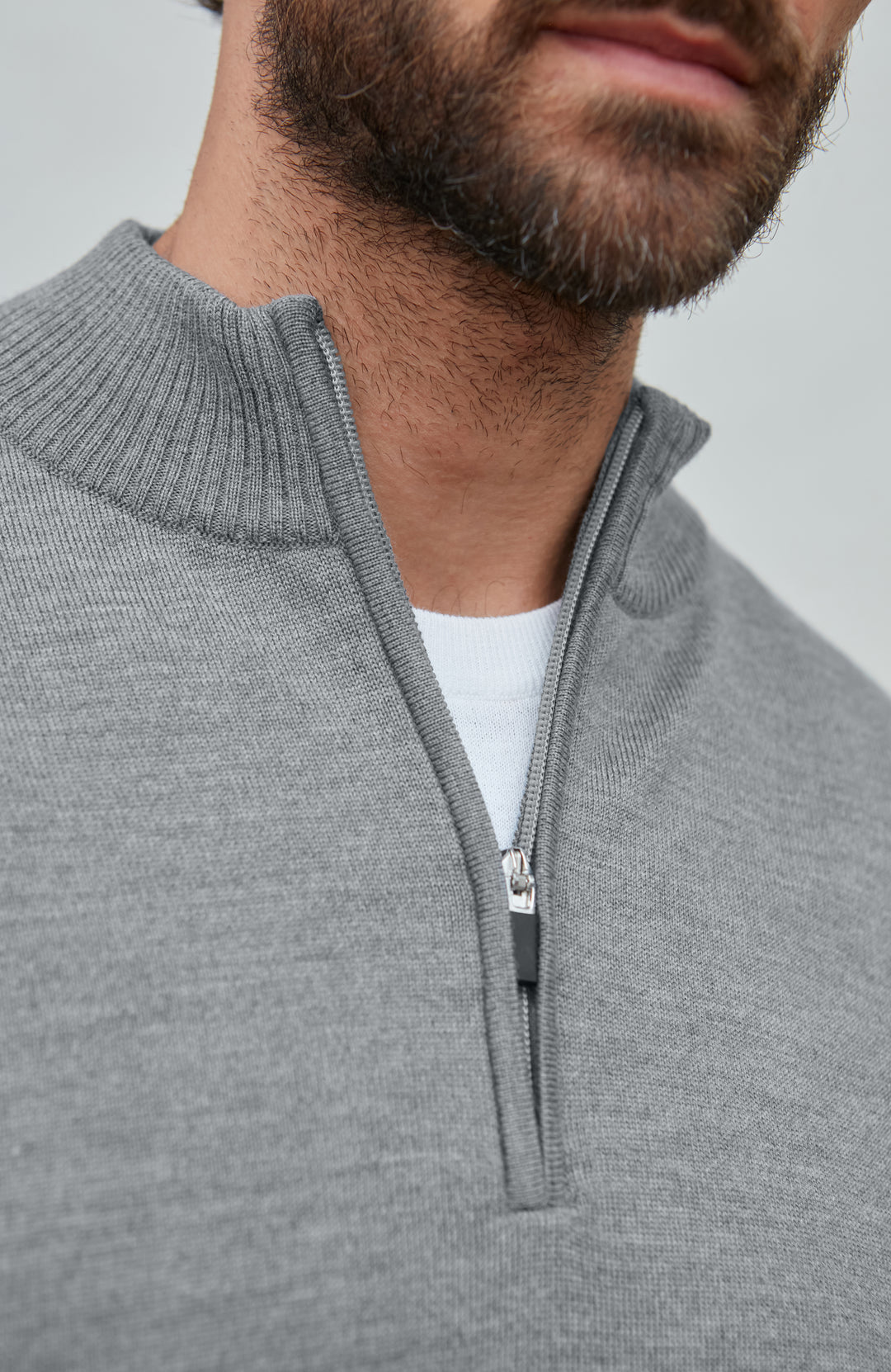 Man wearing a gray fine merino wool quarter-zip sweater against a light gray background