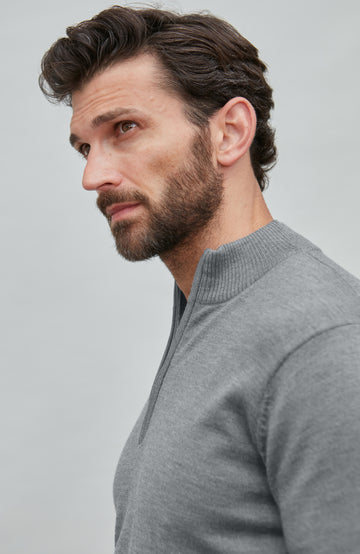 Man wearing a gray fine merino wool quarter-zip sweater against a light gray background
