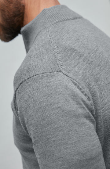 Man wearing a gray fine merino wool quarter-zip sweater against a light gray background