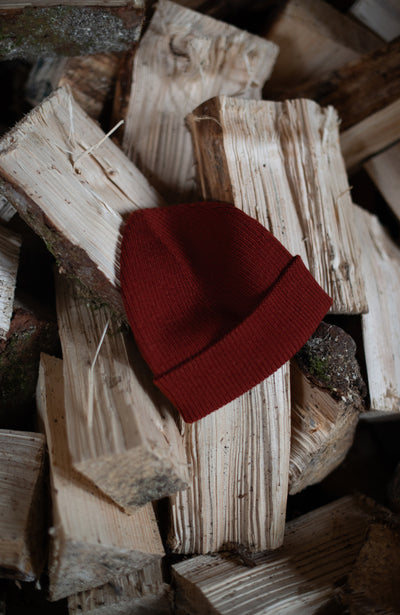 red merino wool womens beanie on logs by paul james knitwear