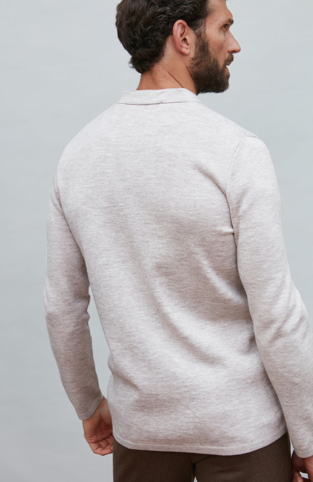 Man wearing a light gray mandarin collar jacket against a plain background by Paul James