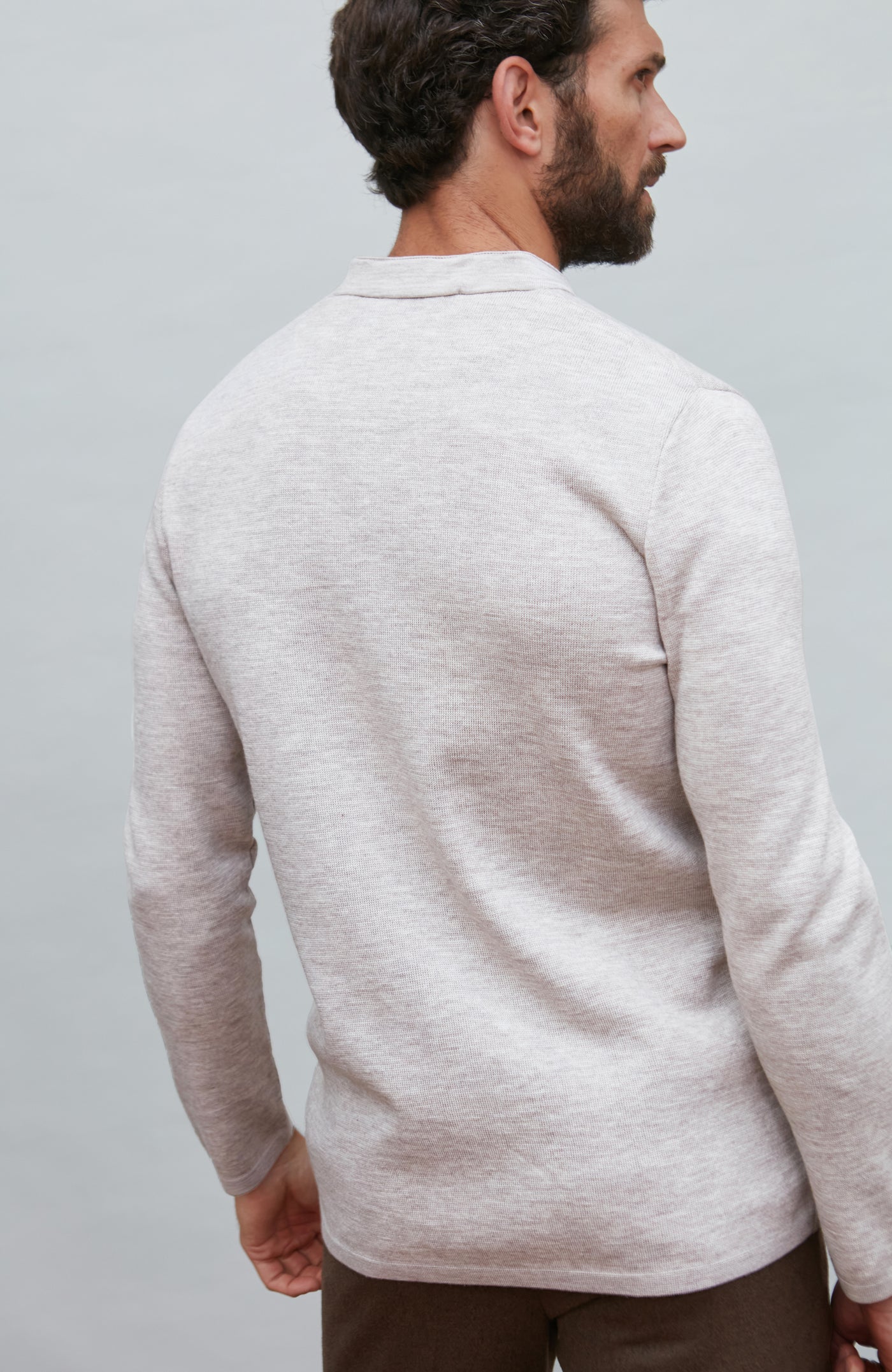 Man wearing a light gray mandarin collar jacket against a plain background