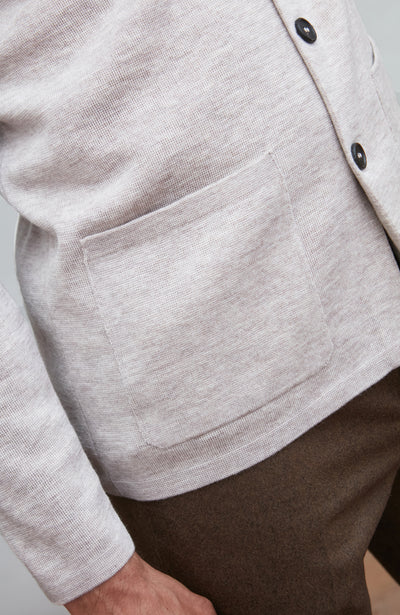 Close-up of a light gray mandarin collar jacket with button details on a neutral background