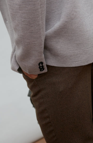 Man wearing a grey fine merino wool blazer over a gray shirt with a plain background