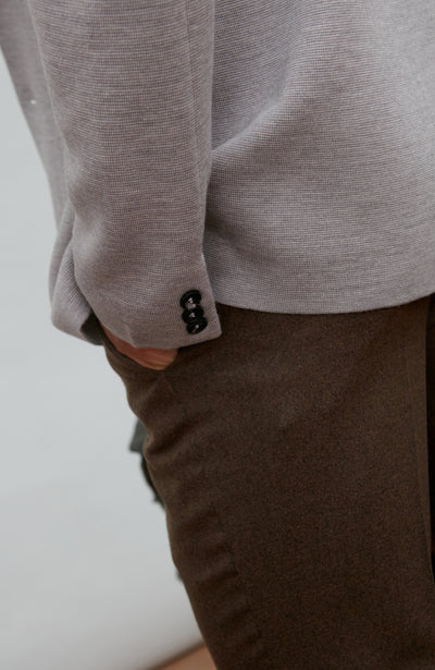 Man wearing a grey fine merino wool blazer over a gray shirt with a plain background