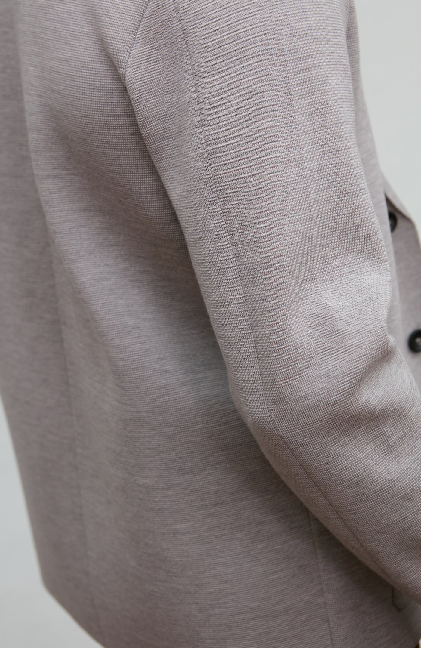 Close-up of a gray wool blazer sleeve on a light background