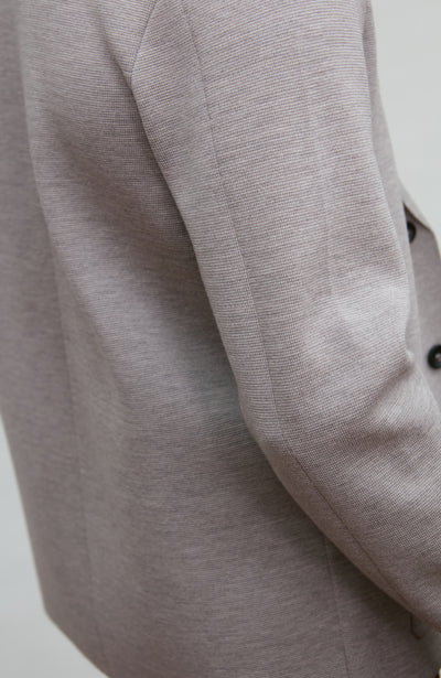 Close-up of a gray wool blazer sleeve on a light background