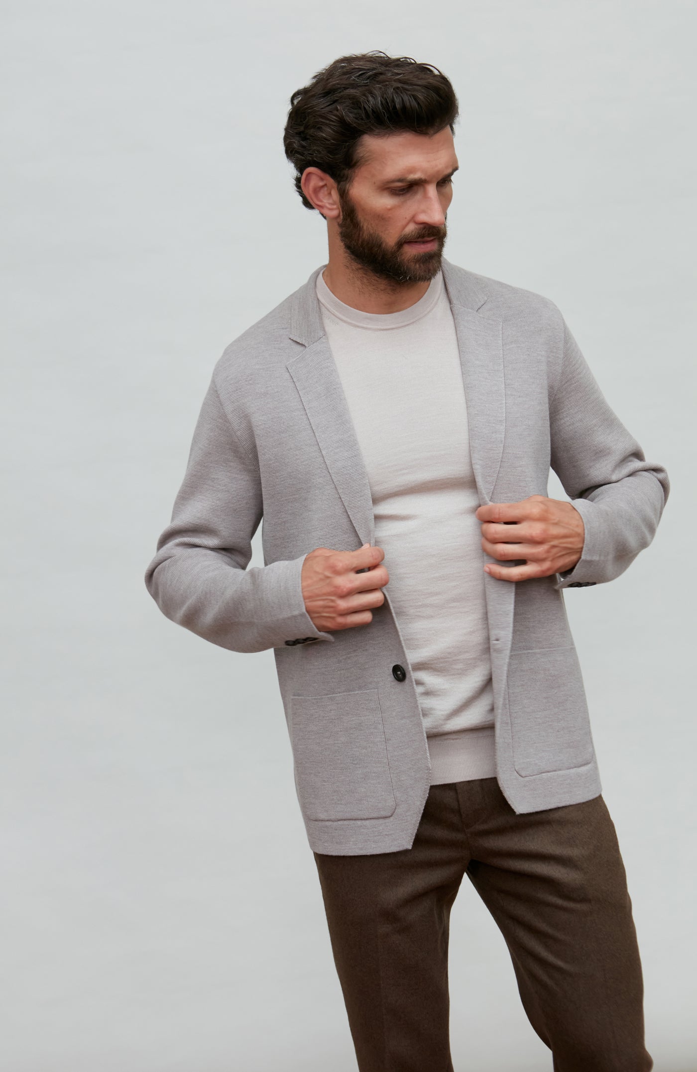 Man wearing a gray fine wool blazer over a white shirt with a plain background