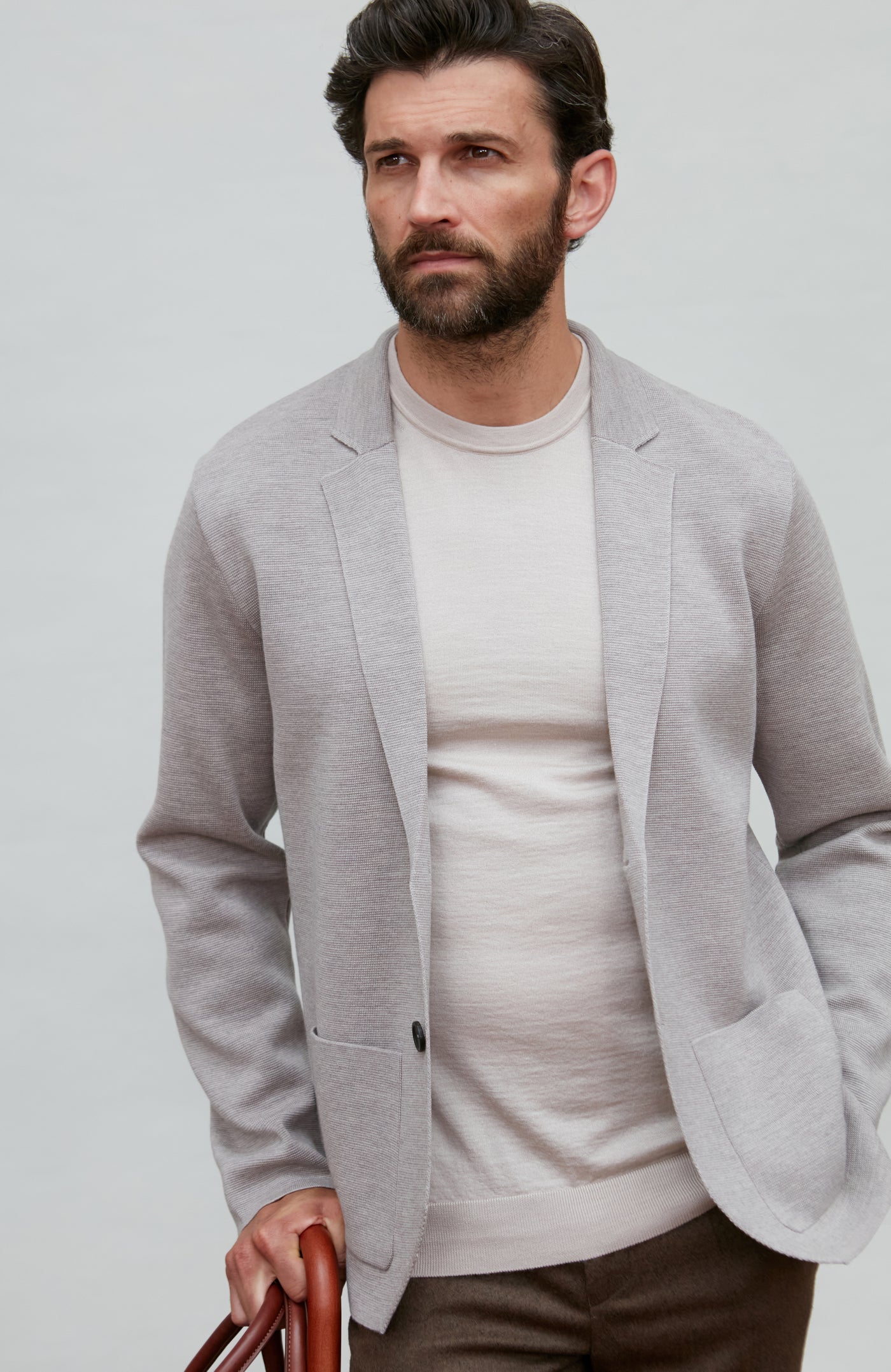 Man wearing a light gray fine wool blazer over a white shirt on a plain background