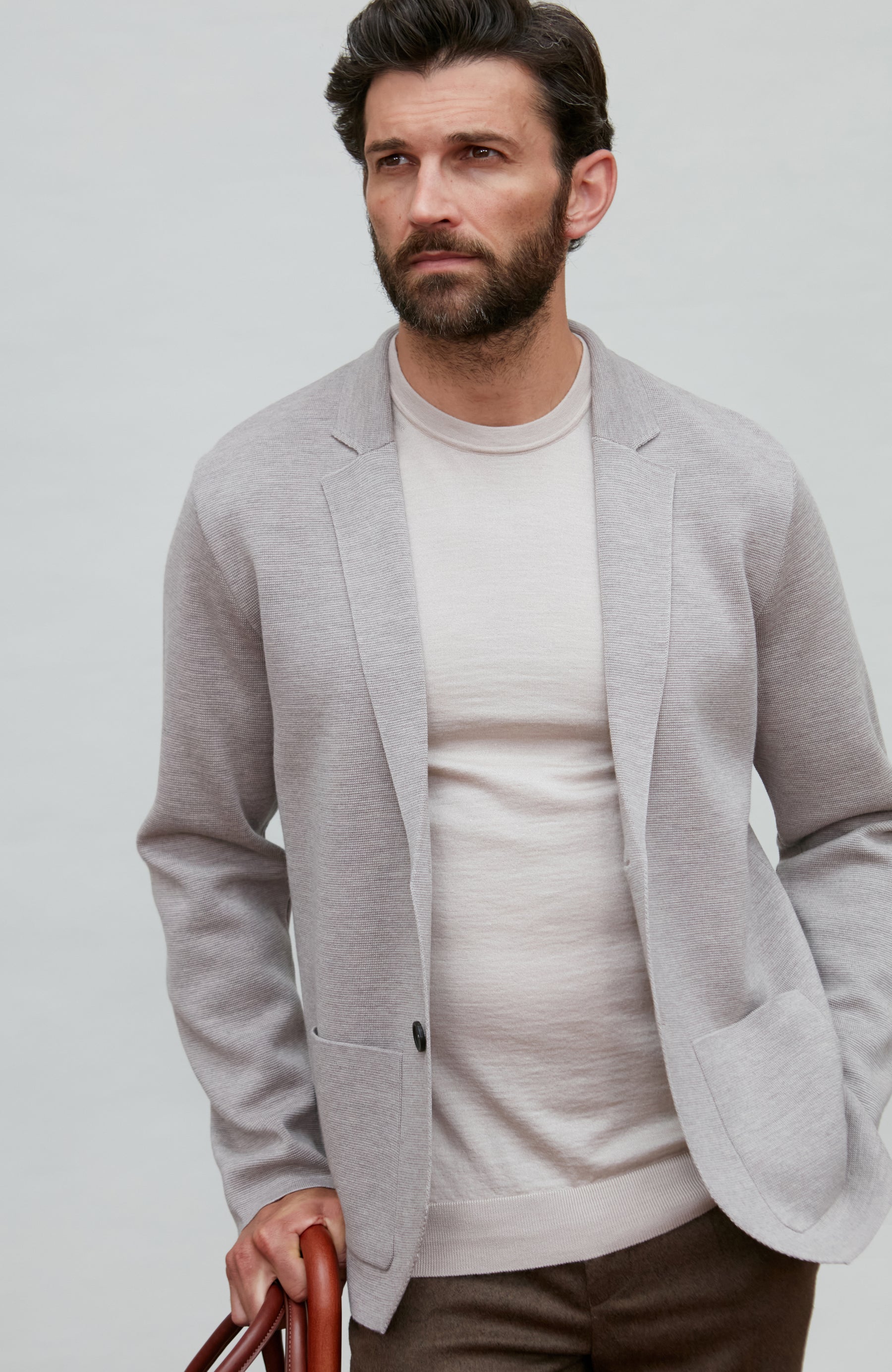 Man wearing a light gray fine wool blazer over a white shirt on a plain background