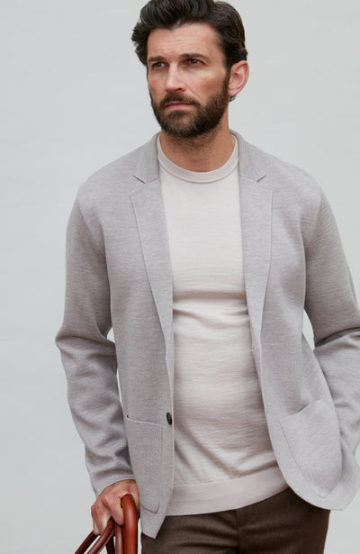 Man wearing a light gray fine wool blazer over a white shirt on a plain background