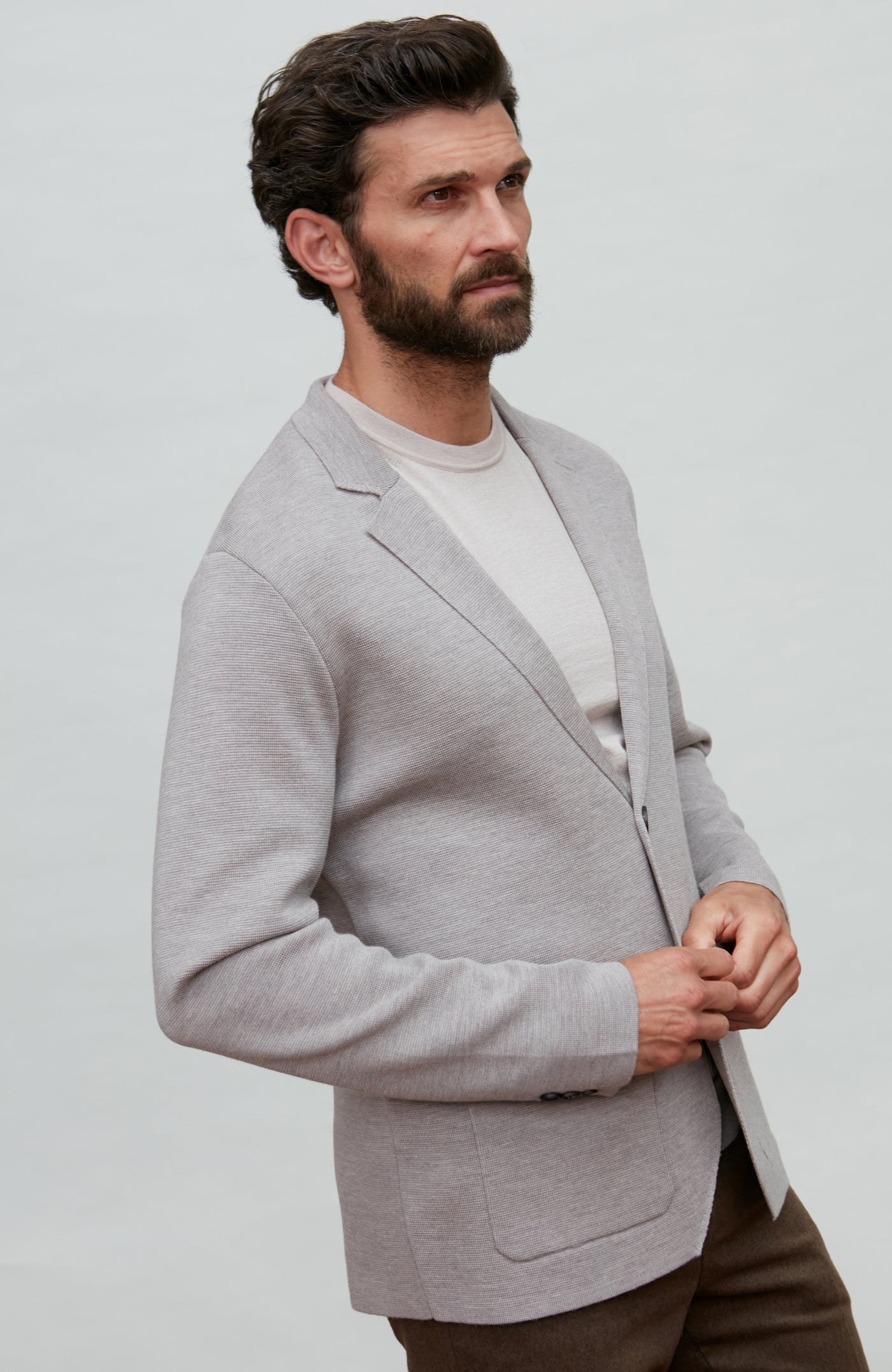 Man wearing a black fine merino wool blazer over a gray shirt with a plain background