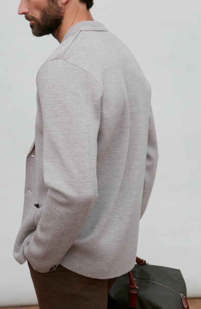 Man wearing a grey fine merino wool blazer over a gray shirt with a plain background