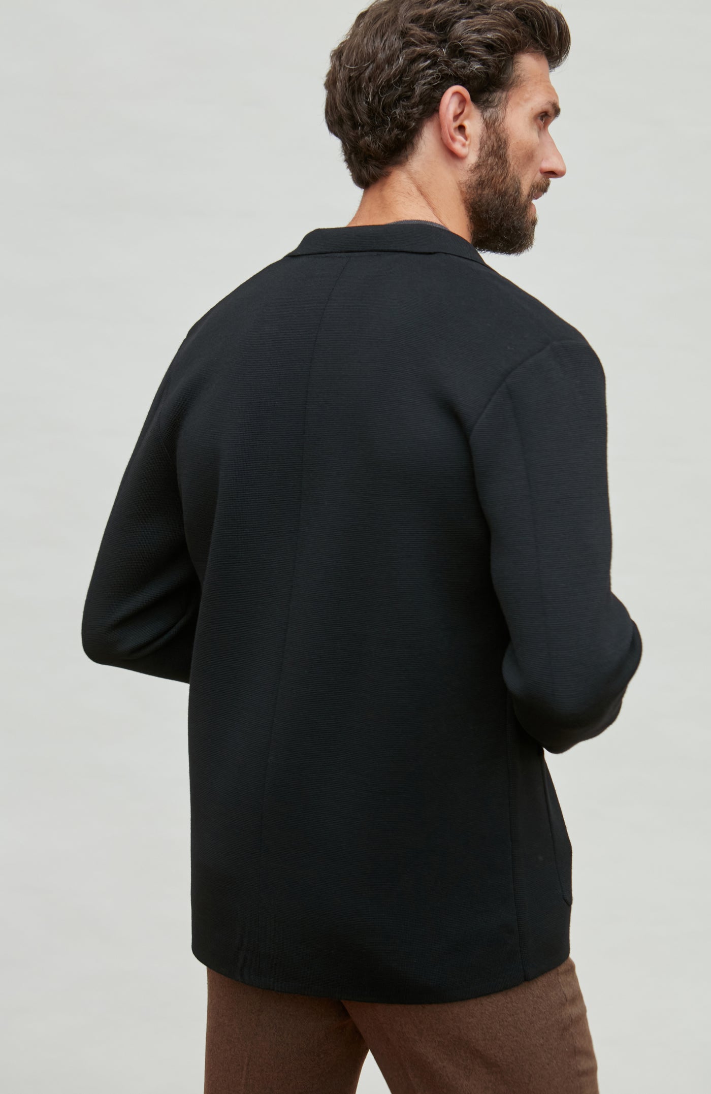 Man wearing a black fine wool jacket on a light gray background