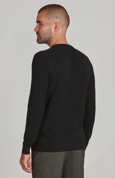 Man wearing a black merino cashmere sweater against a plain background