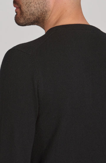 Black merino cashmere sweater worn by a person on a plain background by Paul James
