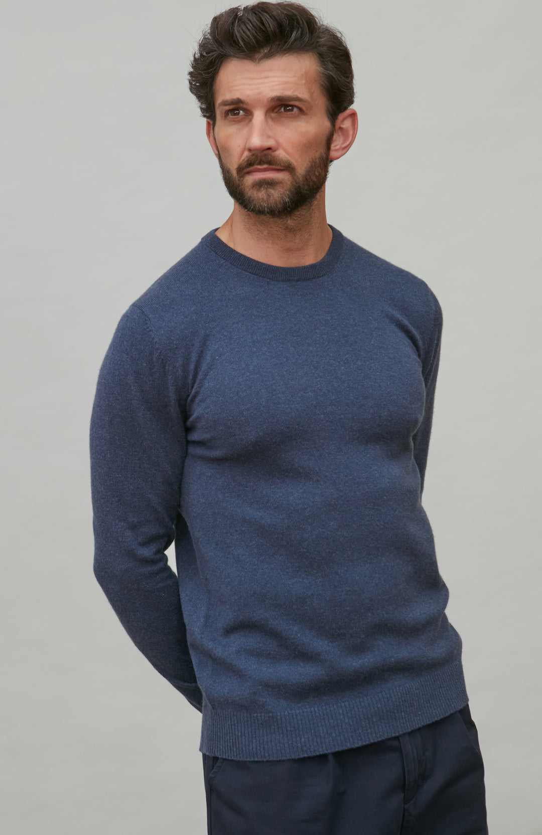 Man wearing a blue merino cashmere  sweater against a gray background by Paul James