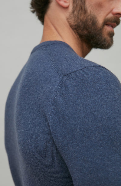 Man wearing a blue merino cashmere sweater against a gray background