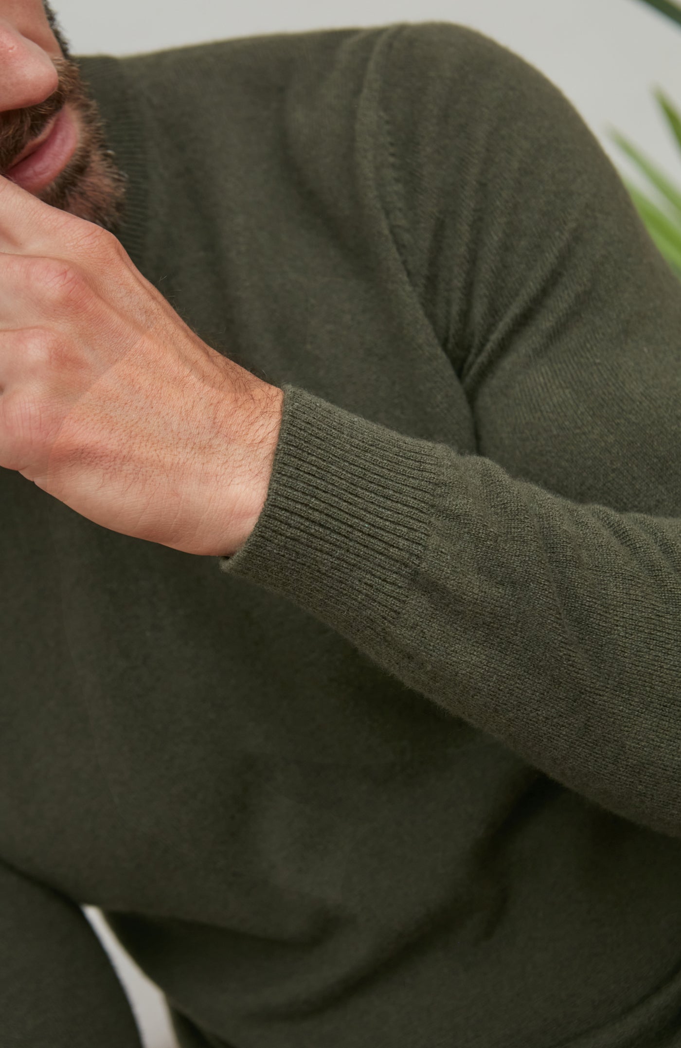Person wearing a green merino cashmere sweater with a blurred background