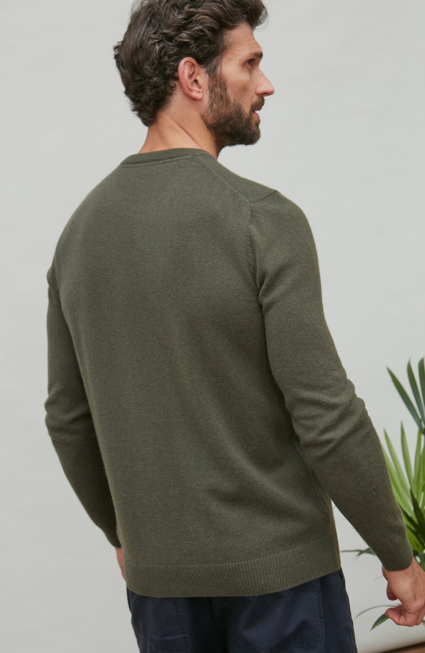 Man wearing a green merino cashmere crew neck sweater against a plain background
