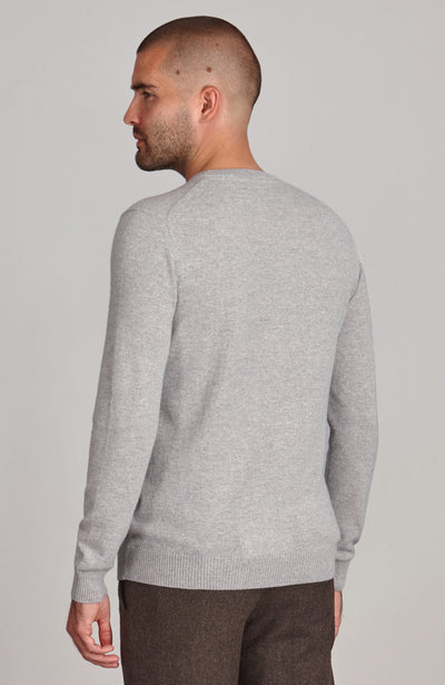 Man wearing a merino cashmere crew neck sweater and brown pants against a plain background