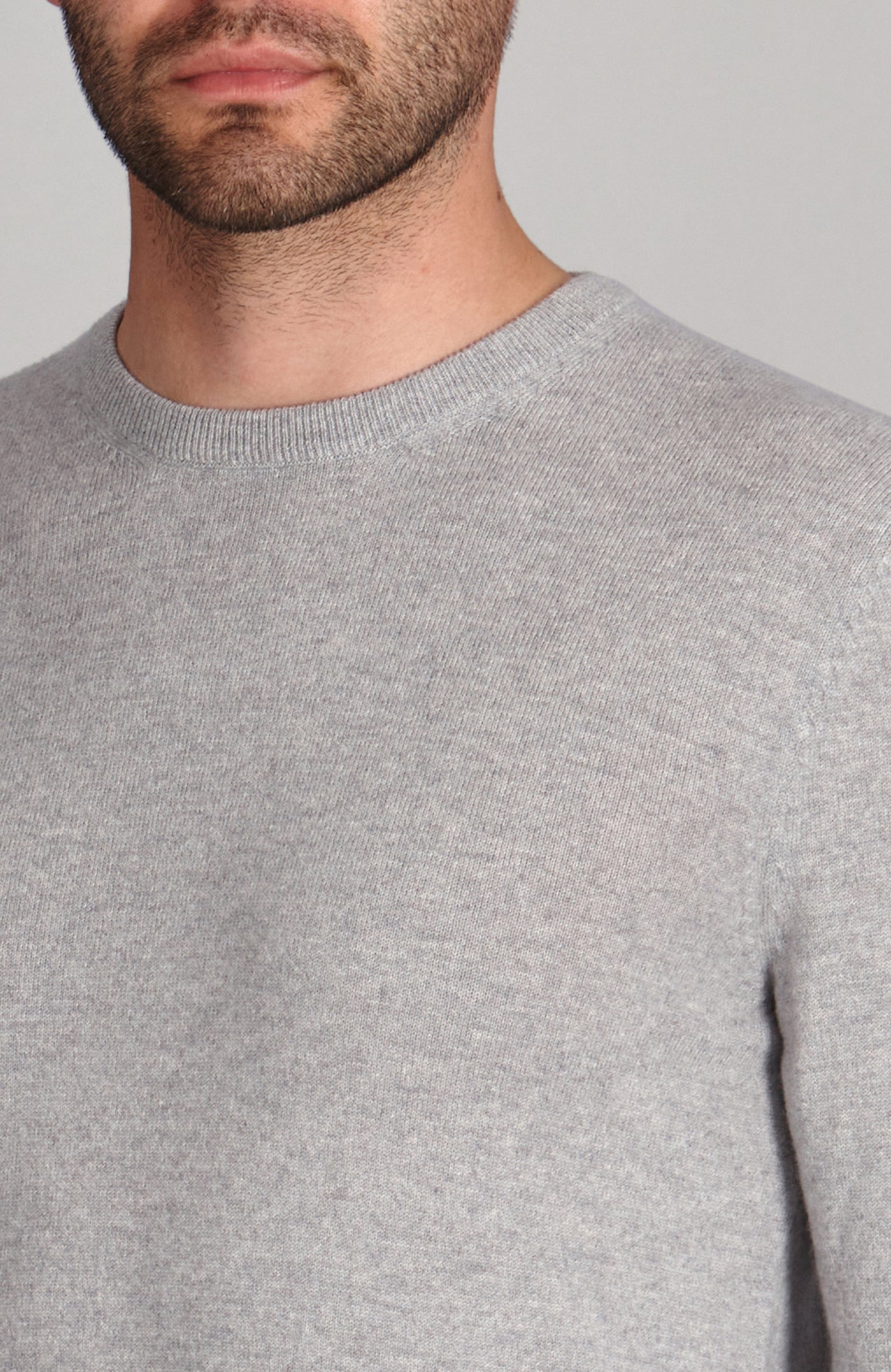 Gray merino cashmere crew neck sweater worn by a person on a plain background