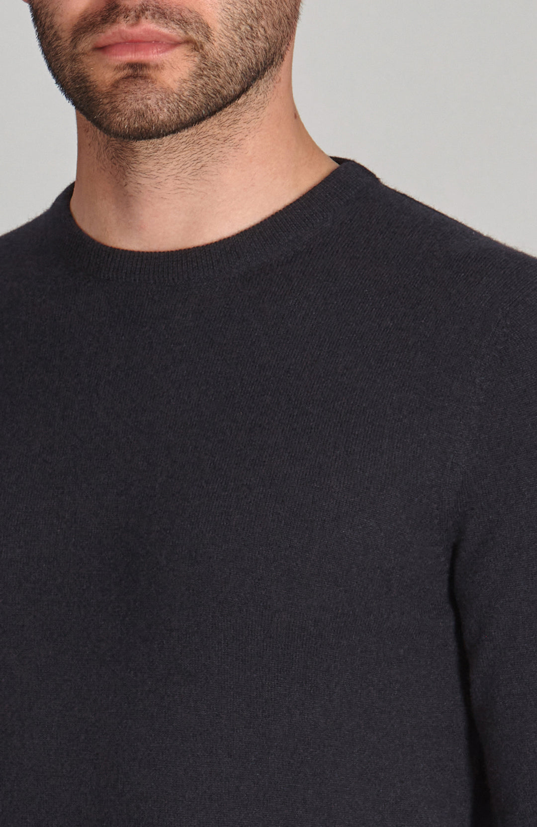 Man wearing a navy merino cashmere crew neck sweater against a gray background by Paul James