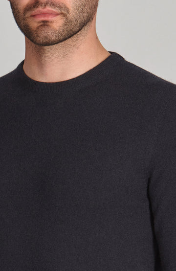 Man wearing a navy merino cashmere crew neck sweater against a gray background by Paul James