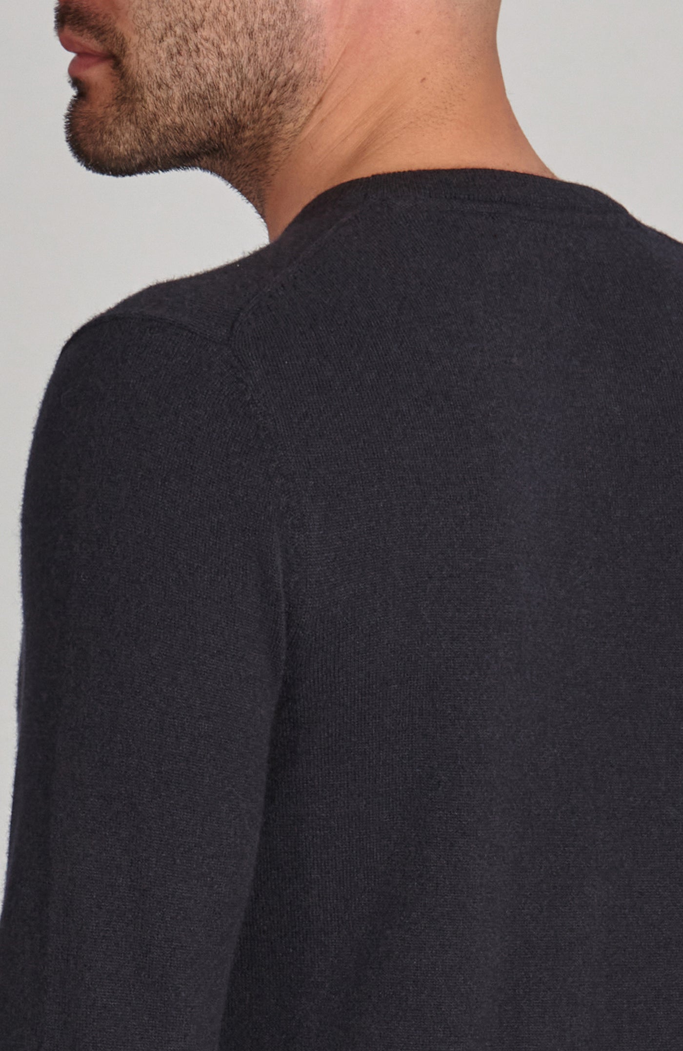 Person wearing a black merino cashmere crew neck long-sleeve shirt against a light gray background