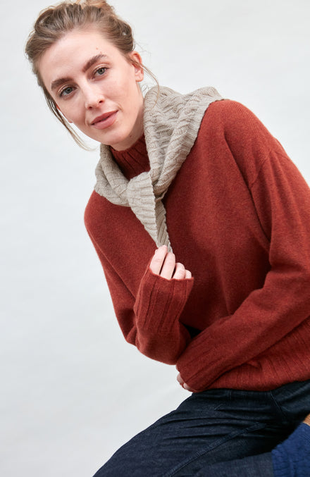 Woman wearing a beige merino cashere knitted neckerchief against a white background by Paul James 