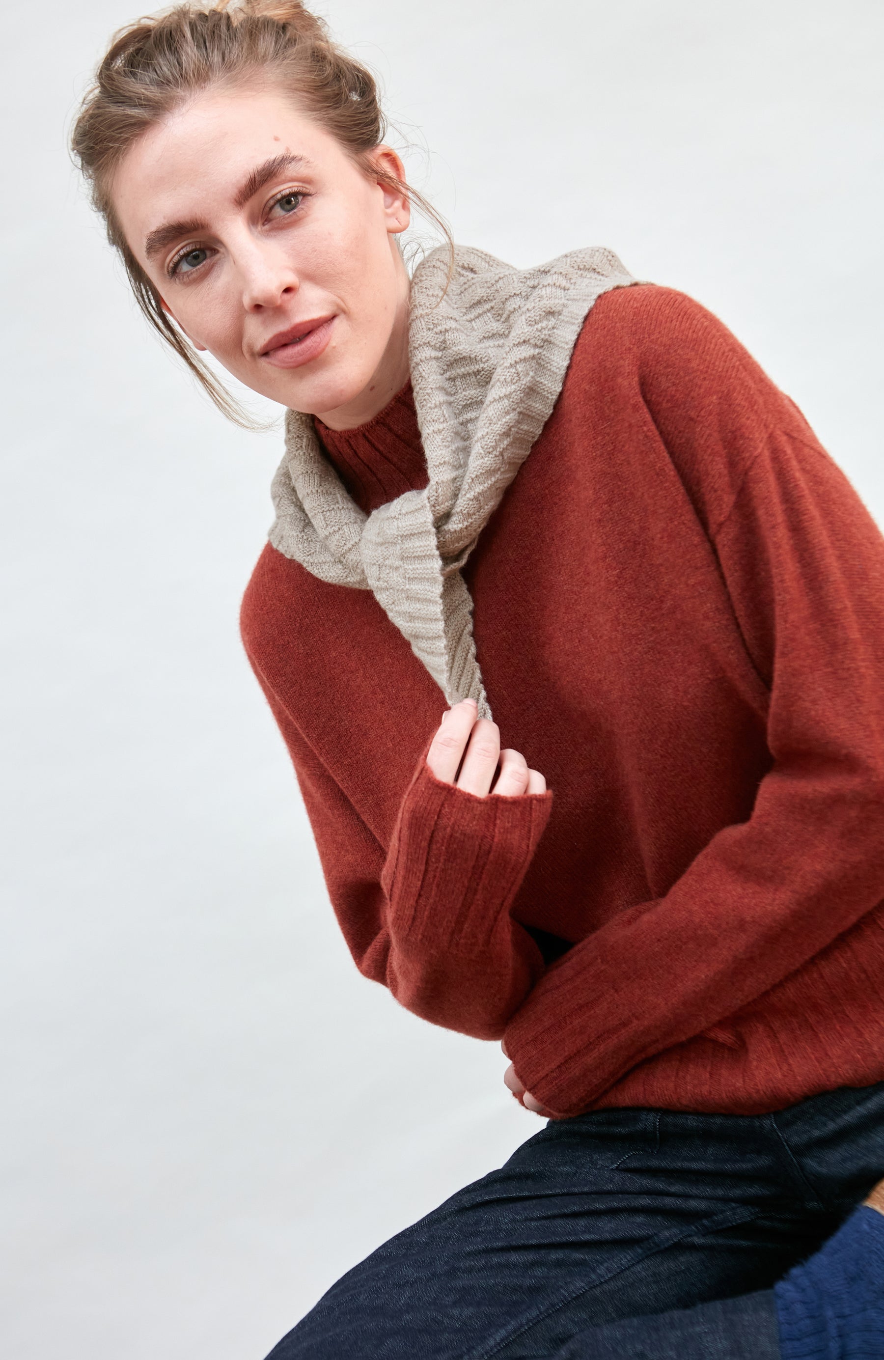 Woman wearing a beige merino cashere knitted neckerchief against a white background
