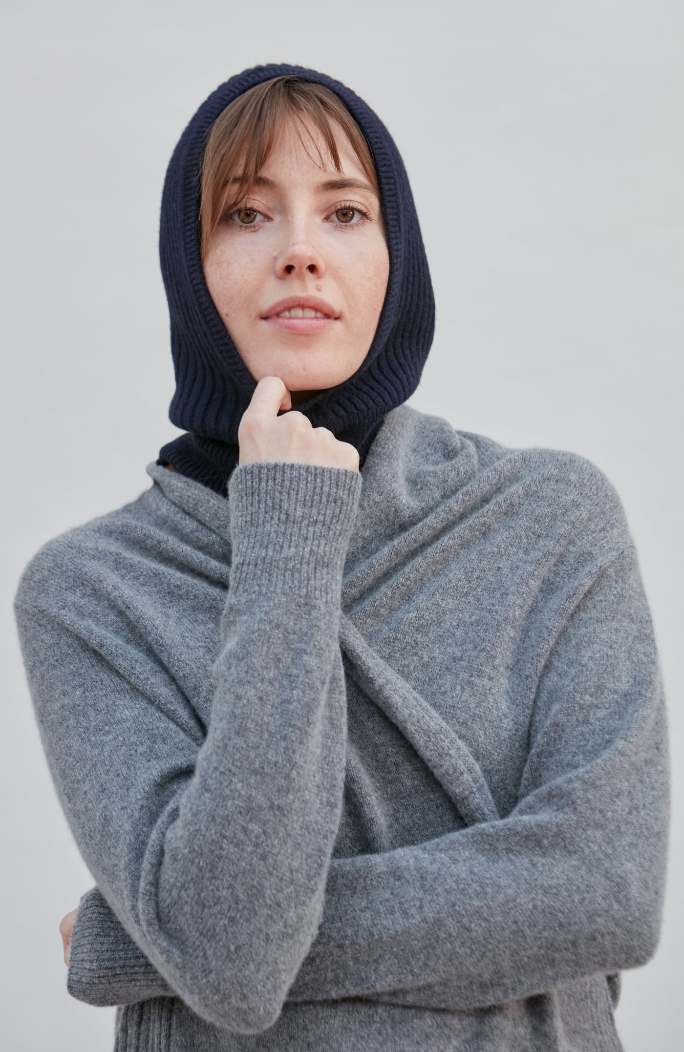 woman wearing a navy merino cashmere balaclava against a plain background