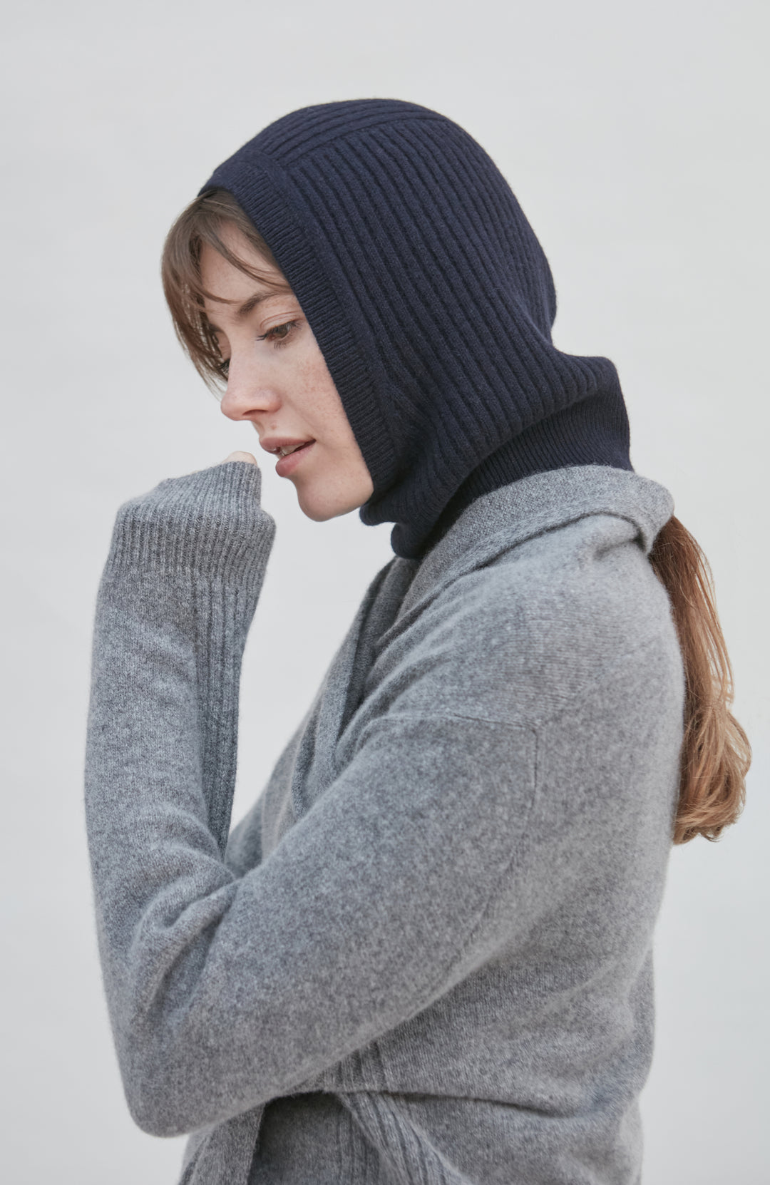 woman wearing a navy merino cashmere balaclava against a plain background by Paul James 