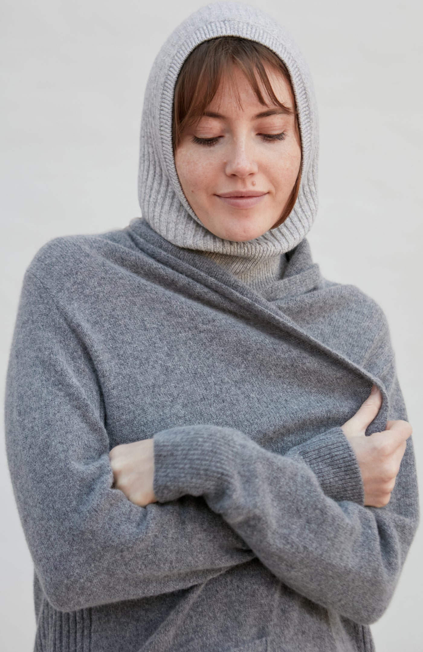 woman wearing a gray merino cashmere balaclava against a plain background