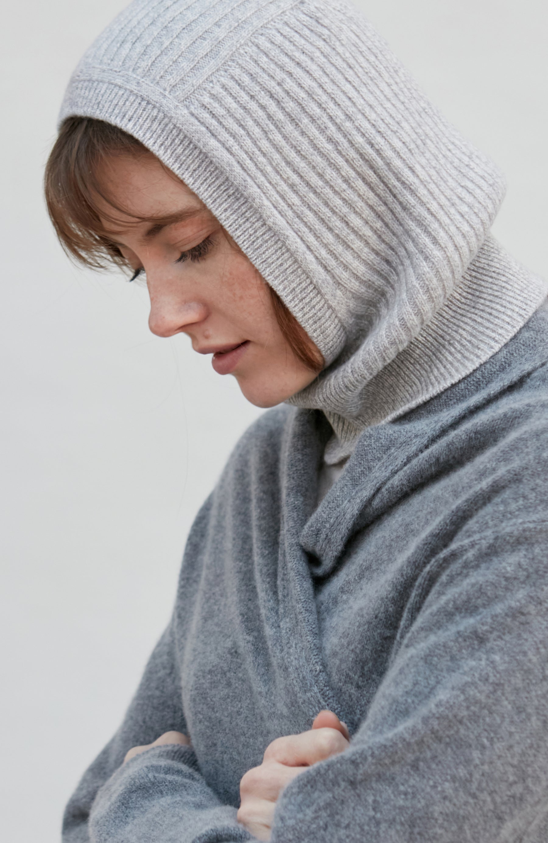 woman wearing a gray merino cashmere balaclava against a plain background