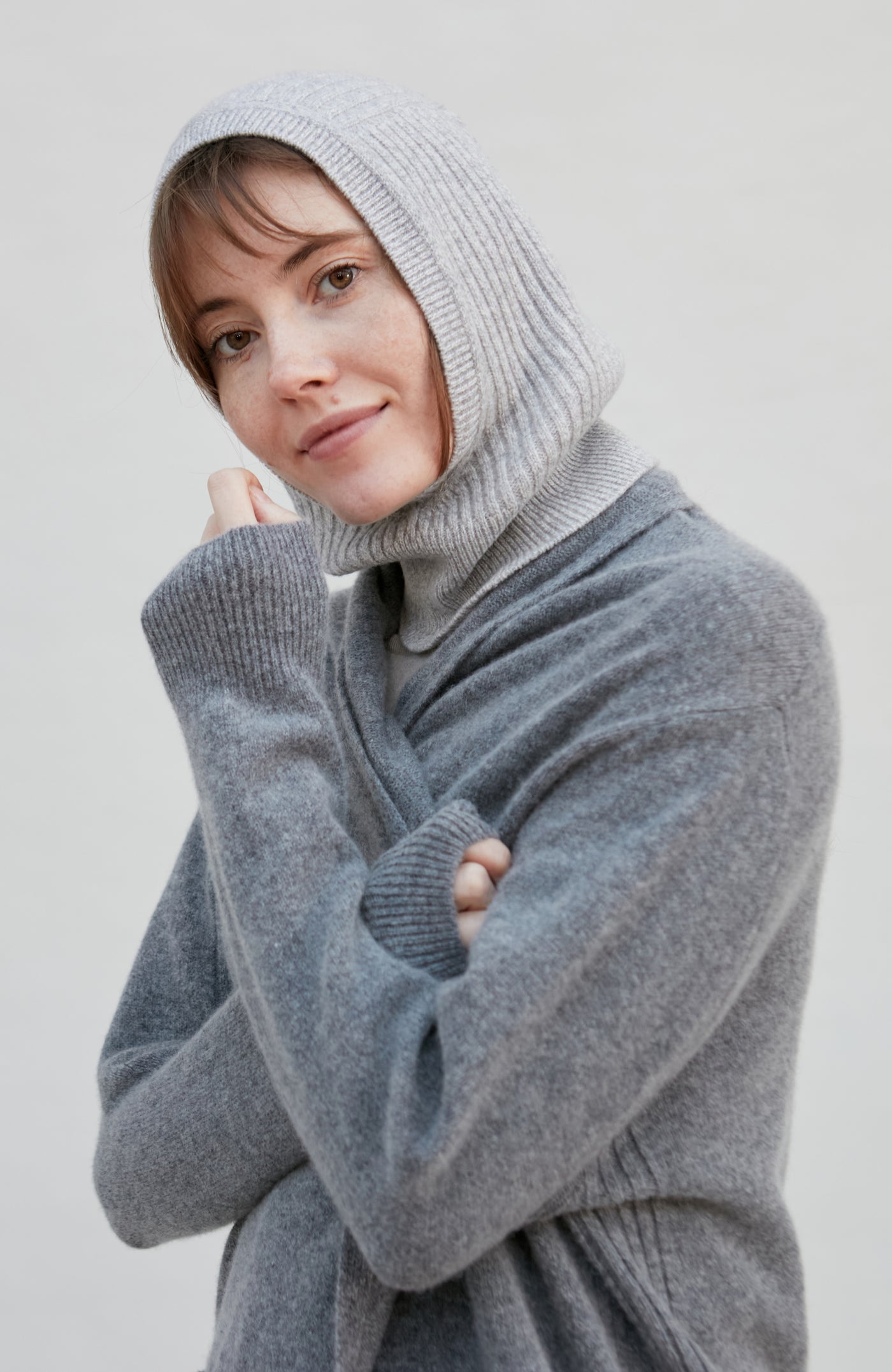 woman wearing a gray merino cashmere balaclava against a plain background